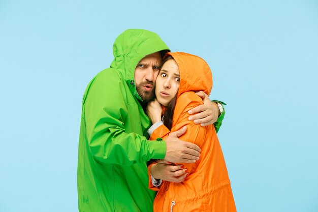 Le jeune couple posant au studio en veste d'automne isolé sur bleu.