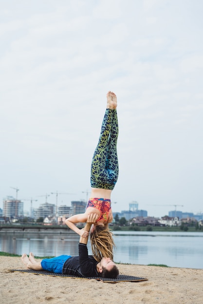 Photo gratuite jeune couple, pratiquer, yoga, sur, ville, arrière-plan