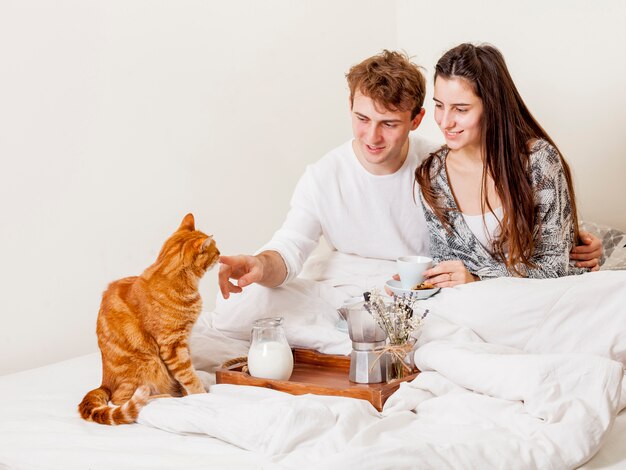 Jeune couple prenant son petit déjeuner au lit