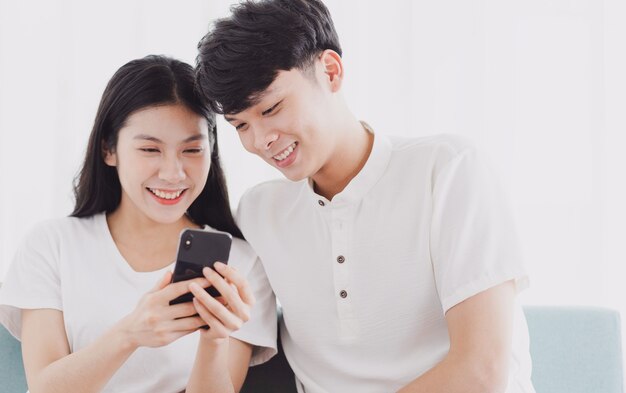Jeune couple regardant le téléphone avec une expression heureuse