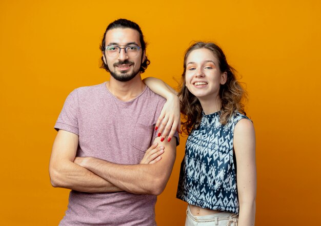 Jeune couple, regarder appareil-photo, sourire, heureux, et, positif, debout, sur, arrière-plan orange