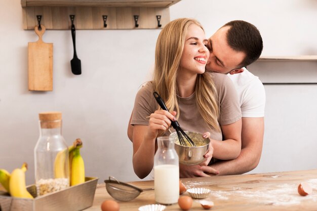 Jeune couple remuer les œufs et le lait dans le bol