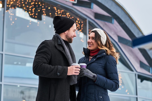 Jeune couple à un rendez-vous près de la patinoire, buvant du café et parlant