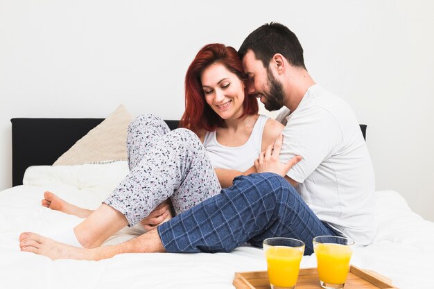 Jeune couple romantique assis sur le lit