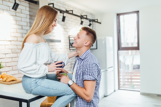 Jeune couple romantique buvant du café ensemble dans la cuisine, s'amusant ensemble.