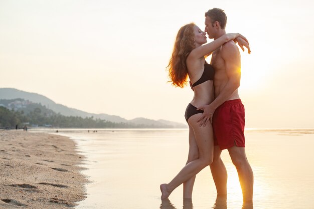 Jeune couple romantique sexy amoureux heureux sur la plage d'été ensemble s'amusant à porter des maillots de bain