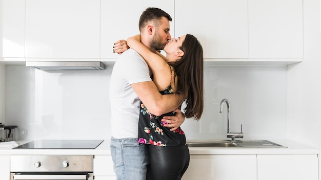 Jeune couple s&#39;embrassant dans la cuisine