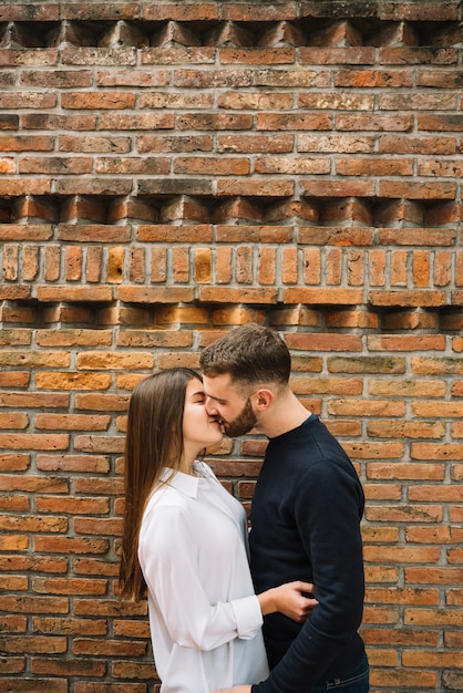 Jeune couple s&#39;embrassant devant le mur