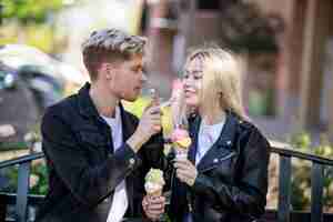 Photo gratuite jeune couple se nourrissant mutuellement de glaces au parc photo de haute qualité