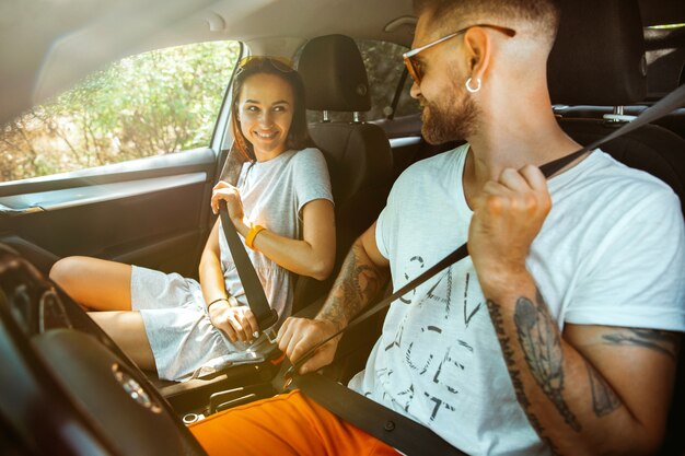 Jeune couple se préparant pour un voyage de vacances sur la voiture en journée ensoleillée.