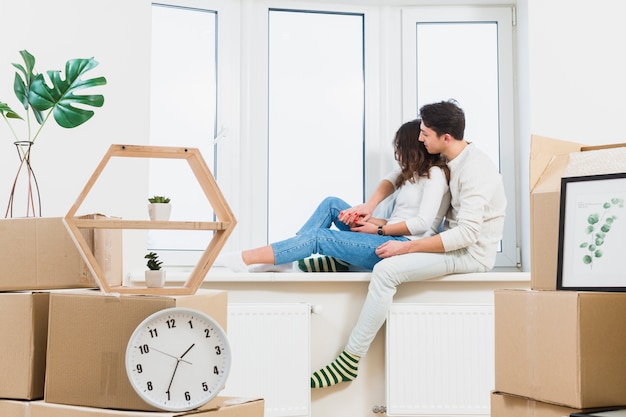 Jeune couple, séance, sur, rebord fenêtre, regarder, par, fenêtre, à, beaucoup, cartons