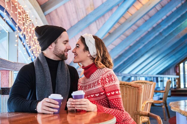 Jeune couple séduisant à un rendez-vous au café, parler et s'embrasser à Noël
