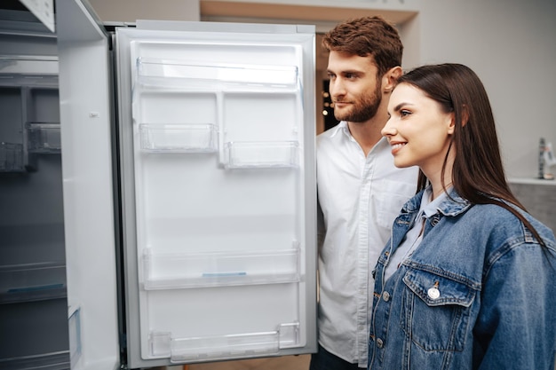 Jeune couple sélectionnant un nouveau réfrigérateur dans un magasin d'électroménagers