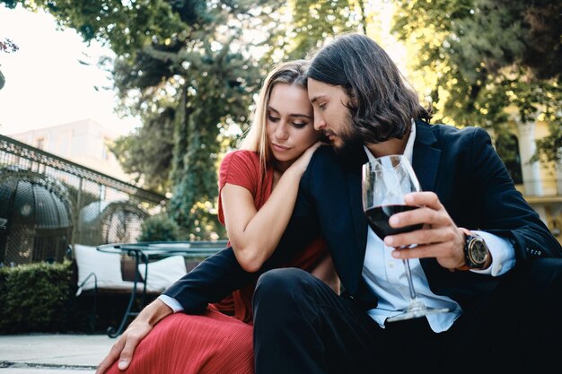 Jeune couple sensuel avec verre de vin rouge à date au restaurant en plein air