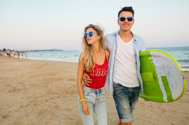 Photo gratuite jeune couple souriant s'amuser sur la plage à marcher avec planche de surf