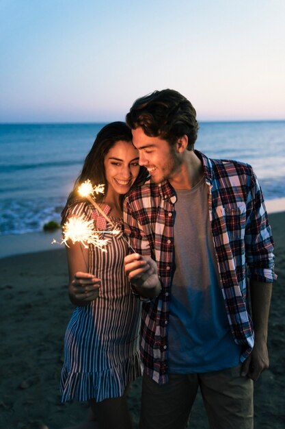 Jeune couple avec sparkler à la plage