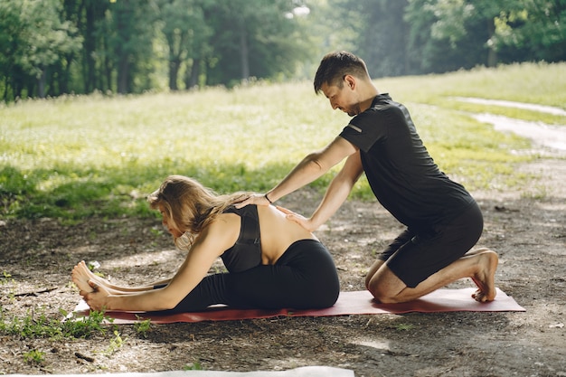 Jeune couple sportif faisant du yoga. Les gens dans un parc d'été.