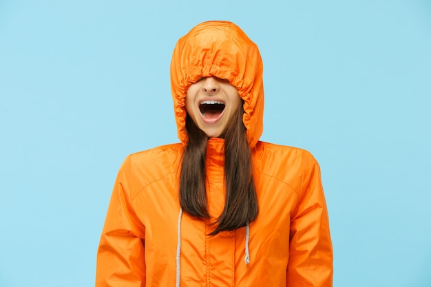 Le jeune couple surpris au studio en vestes d'automne isolé sur bleu. Humaines émotions positives heureuses. Concept du temps froid. Concepts de mode féminine et masculine