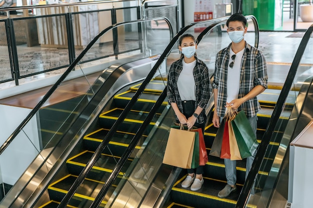 Jeune couple tenant plusieurs sacs en papier