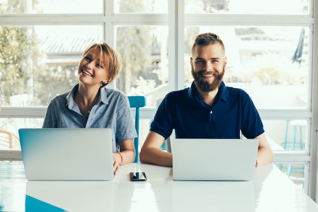 jeune couple travaillant sur des ordinateurs portables dans un café faisant un projet, conférant, pigistes