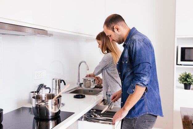 Jeune couple travaillant avec des ustensiles dans la cuisine