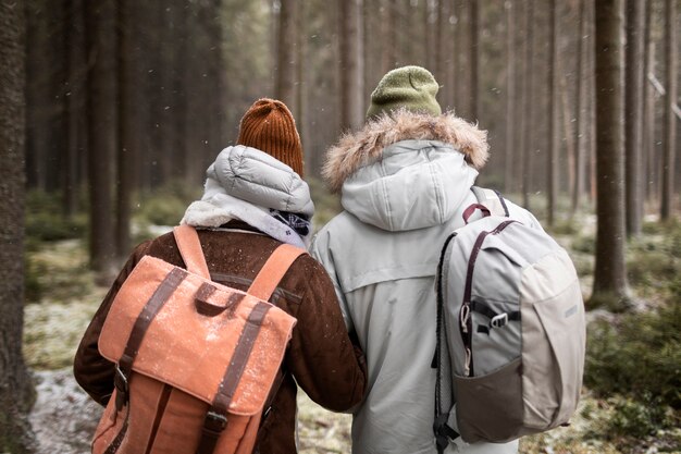 Jeune couple en voyage d'hiver ensemble marchant à travers la forêt