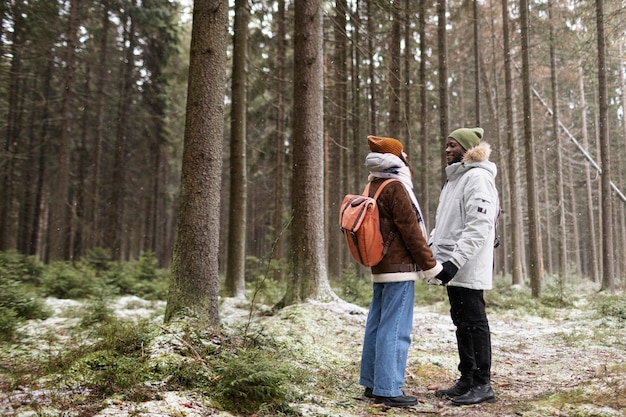 Jeune couple en voyage d'hiver ensemble marchant à travers la forêt