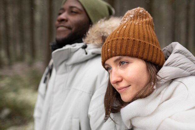 Jeune couple en voyage d'hiver ensemble marchant à travers la forêt