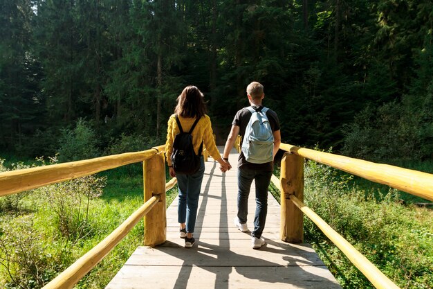 Jeune couple de voyageurs passe sur un pont en bois dans les montagnes