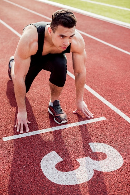 Jeune coureur masculin musclé sur la ligne de départ