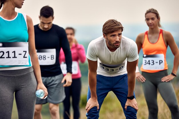 Jeune coureur masculin se sentant épuisé après avoir participé à un marathon dans la nature