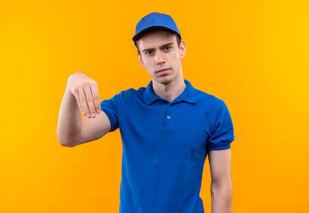 Jeune courrier portant l'uniforme bleu et bonnet bleu faisant sa main vers le bas