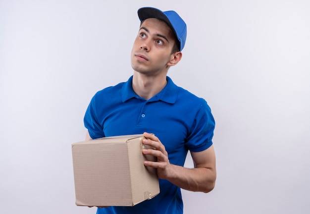 Jeune courrier portant l'uniforme bleu et casquette bleue détient une boîte