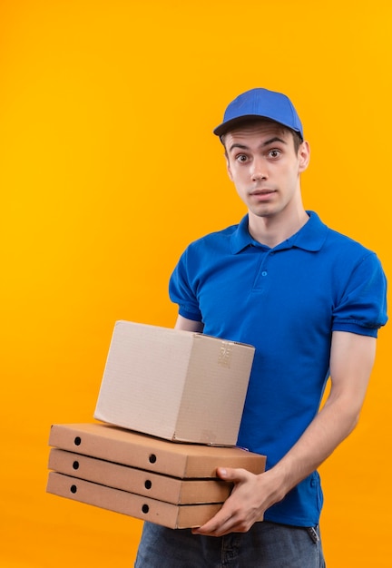 Jeune courrier portant l'uniforme bleu et casquette bleue peur tient des boîtes