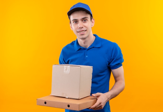 Jeune courrier portant l'uniforme bleu et casquette bleue sourit et détient fort