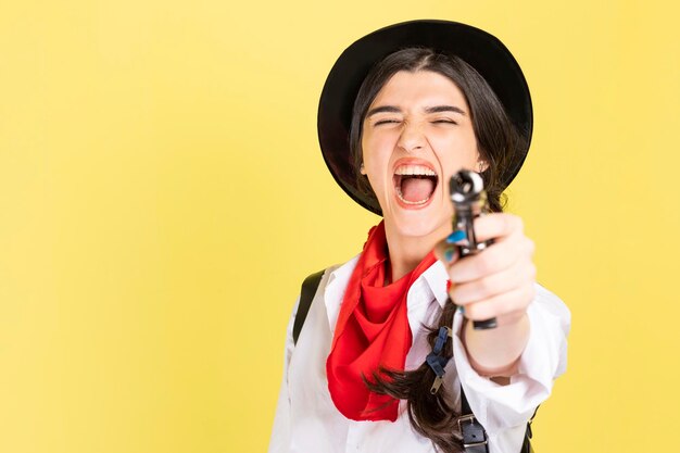 Une jeune cow-girl folle en colère pointe son arme vers l'appareil photo Photo de haute qualité