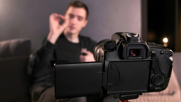 Jeune créateur de contenu parlant et faisant des gestes à l'homme se filmant à l'aide d'une caméra sur un trépied