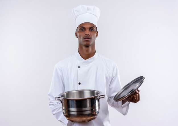 Jeune cuisinier afro-américain confiant en uniforme de chef tient une casserole sur fond blanc isolé avec copie espace