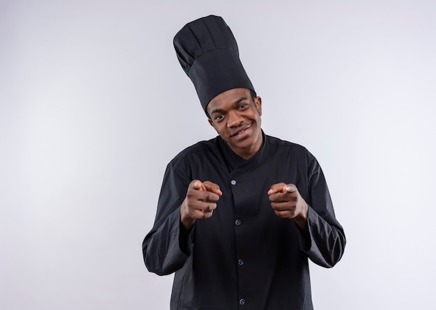 Jeune cuisinier afro-américain heureux en uniforme de chef avec les deux mains isolé sur mur blanc