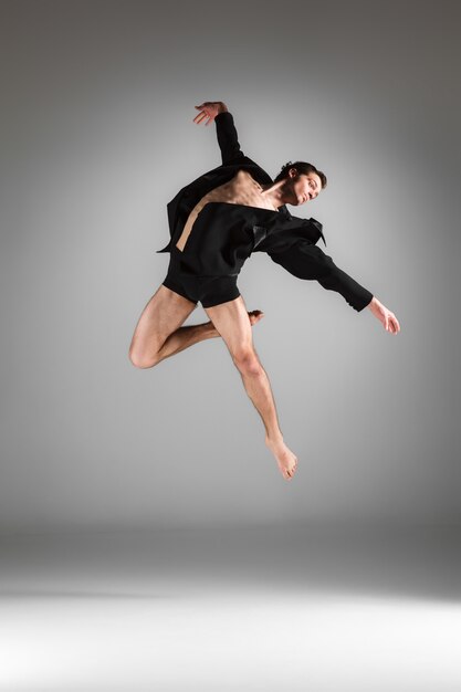 Le jeune danseur de ballet moderne attrayant sautant sur fond blanc