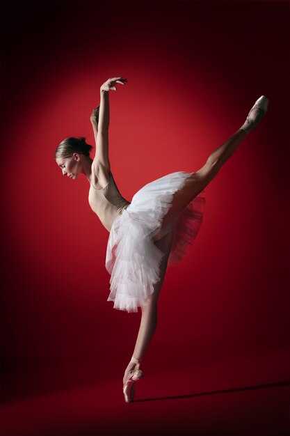 Jeune danseuse de ballet gracieuse ou ballerine classique dansant au studio rouge.