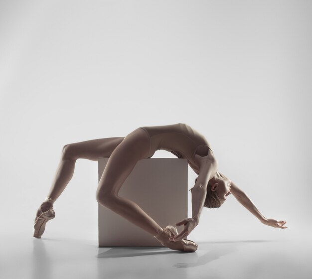 Jeune danseuse de ballet gracieuse ou ballerine classique dansant sur studio blanc.