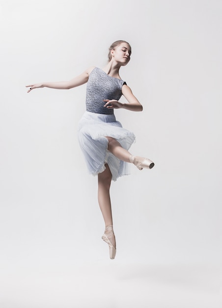 Jeune danseuse classique isolée sur espace blanc.