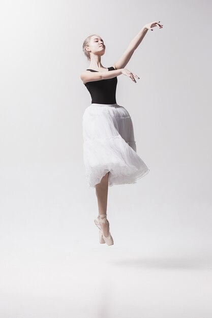 Jeune danseuse classique isolée sur espace blanc.