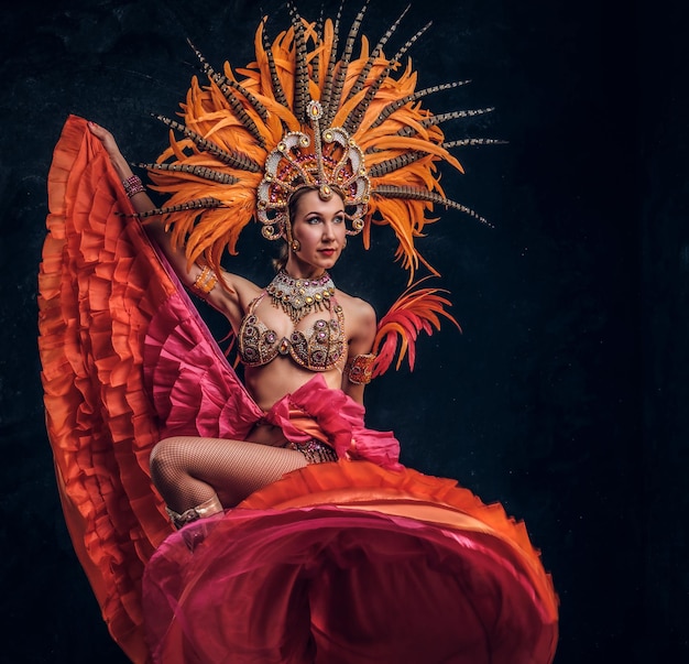 Une jeune danseuse séduisante en costume spécial de plumes danse au studio.