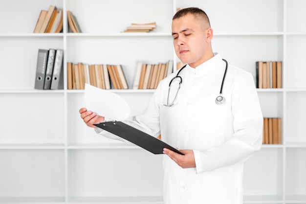 Jeune docteur, regarder, feuilles, presse-papiers