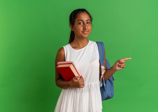 Photo gratuite jeune écolière portant sac à dos tenant un cahier avec livre et points sur le côté