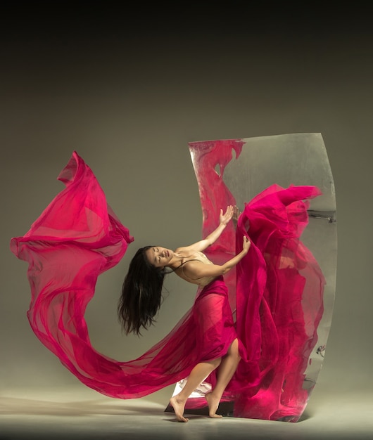 Photo gratuite jeune et élégant danseur de ballet moderne sur marron avec miroir