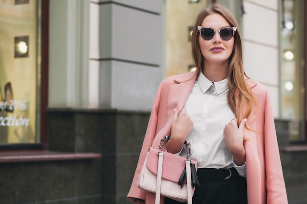 Jeune élégante belle femme marchant dans la rue, portant un manteau rose