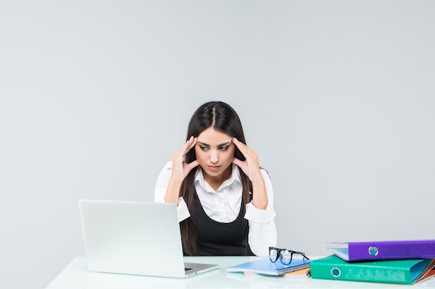 Jeune employée de bureau fatiguée, fatiguée et épuisée en costume gris sur blanc